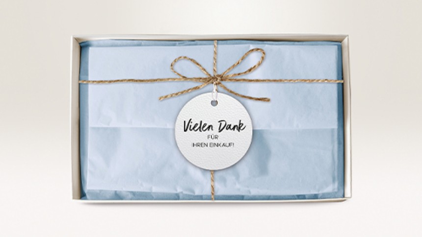 Caja de regalo con etiqueta "Gracias por su compra" y lazo de cordel