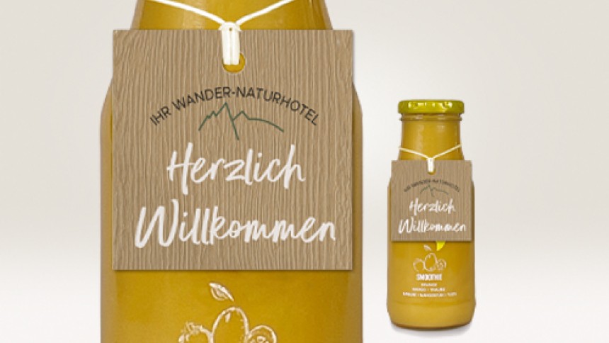 Dos botellas de zumo con etiquetas colgantes de material efecto madera personalizadas con texto
