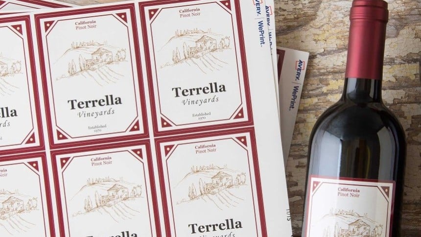 Botella de vino con etiqueta rectangular personalizada. Al lado,una hoja de etiquetas con el mismo diseño
