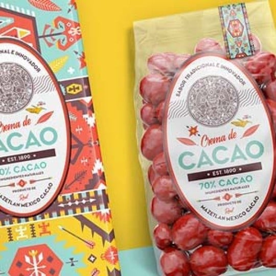 Barra de crema de cacao con diseño colorido y etiqueta ovalada junto a una bolsa transparente llena de bombones rojos