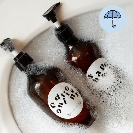 Dos botellas de champú con etiquetas resistentes al agua sumergidas en un baño con jabón
