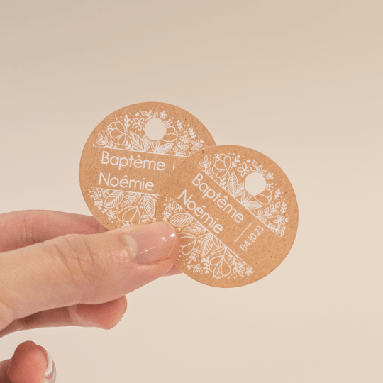 Una mano sujeta dos etiquetas colgantes redondas personalizadas