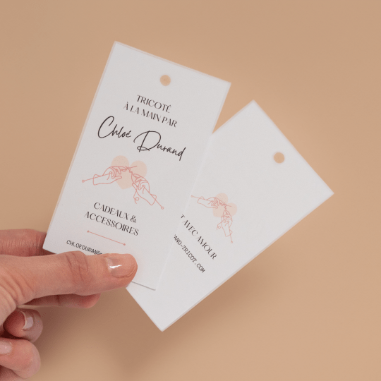 Una mano sujeta dos etiquetas colgantes personalizadas
