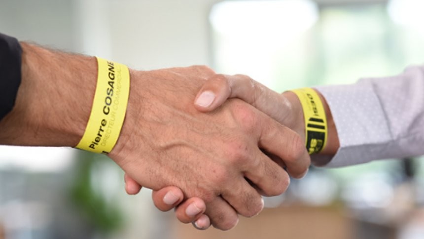 Primer plano de un apretón de manos con pulseras amarillas de evento