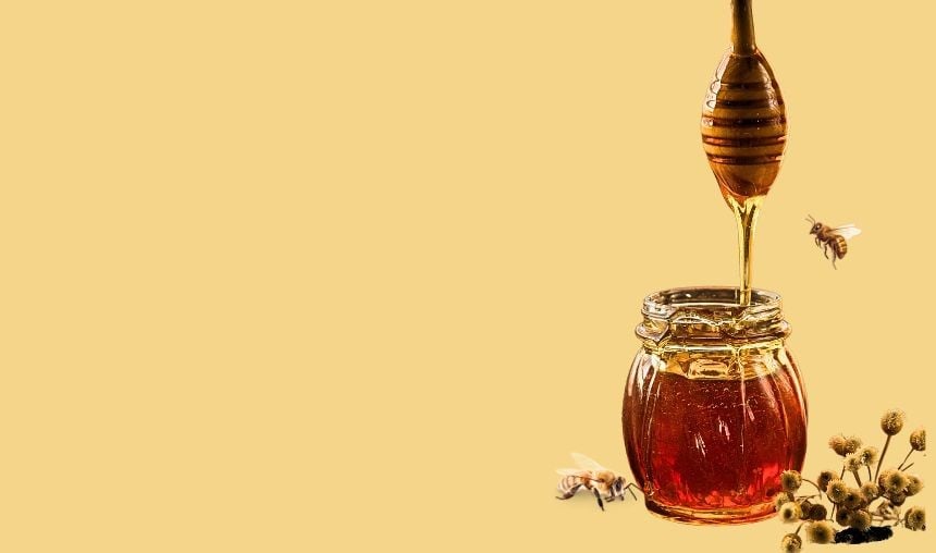Un tarro lleno de miel con un cucharón de madera dentro, del que gotea miel. Dos abejas vuelan alrededor del tarro