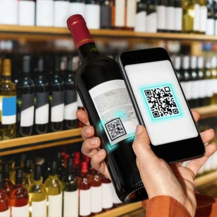 Una señora escanea el código QR de la etiqueta de la botella de vino con su móvil