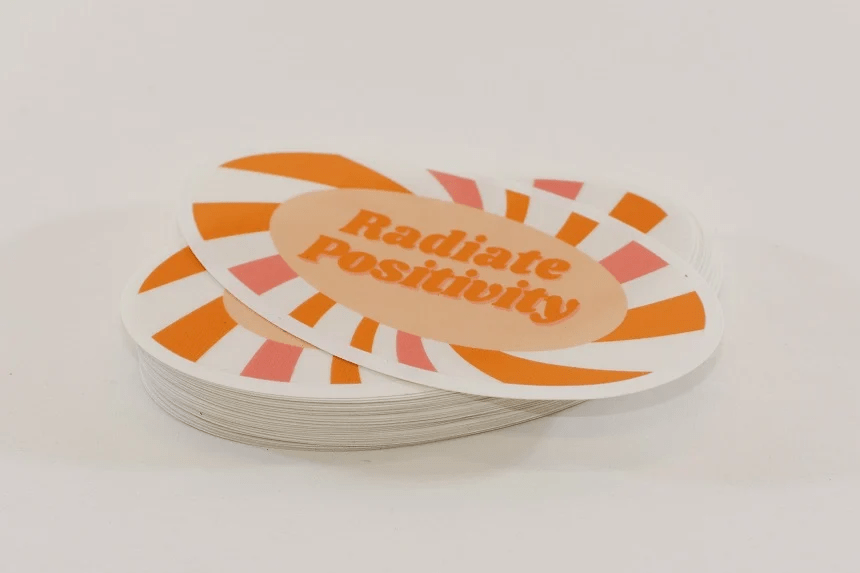 Pegatinas ovaladas naranjas con las palabras "irradia positividad"
