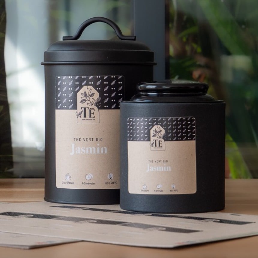 Dos recipientes de té con etiquetas de papel kraft personalizadas y una hoja de etiquetas de papel kraft