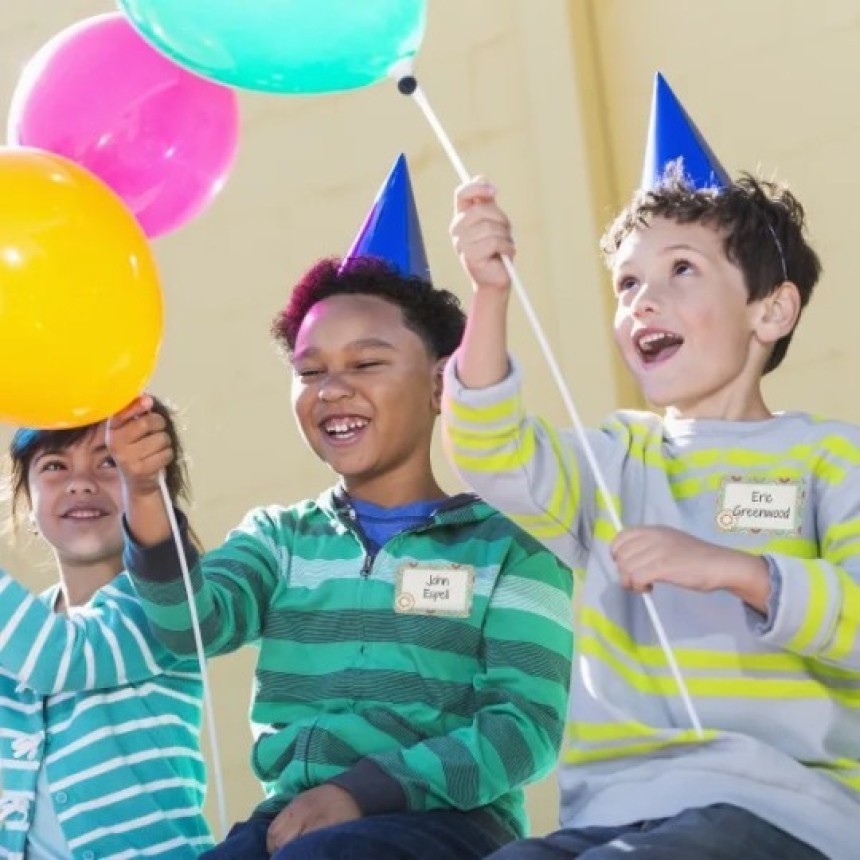Tres niños están en una fiesta. Los niños llevan un identificativo adhesivo con su nombre