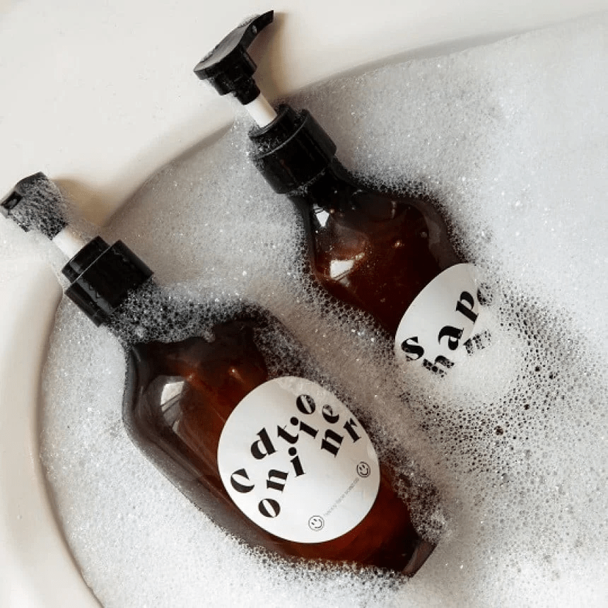 Dos botellas de champú con etiquetas resistentes al agua sumergidas en un baño con jabón