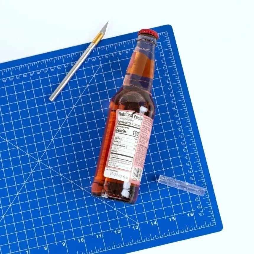 Cuchilla junto a una botella para quitar la etiqueta