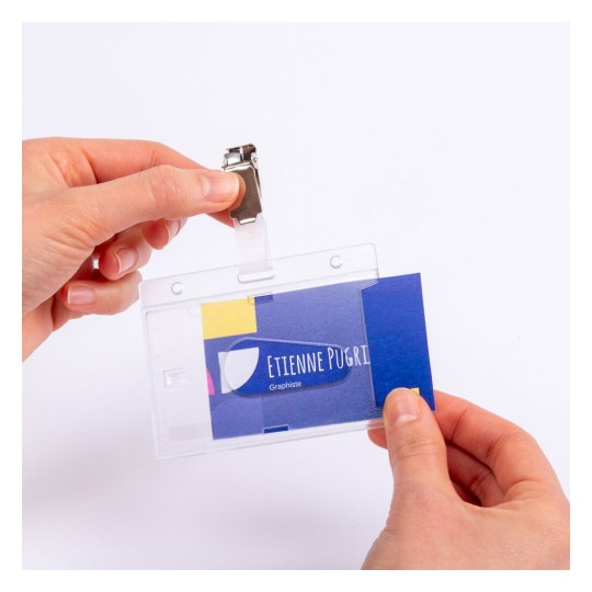 En la imagen se muestra una persona sosteniendo un portatarjetas transparente con una tarjeta de presentación dentro. La tarjeta tiene el nombre 'Etienne Pugri' y la palabra 'Graphiste'.