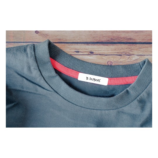 Esta imagen muestra un primer plano del cuello de una camiseta de color gris, con un detalle de una etiqueta que dice 'B. Dubois' y un borde interno de color rojo.