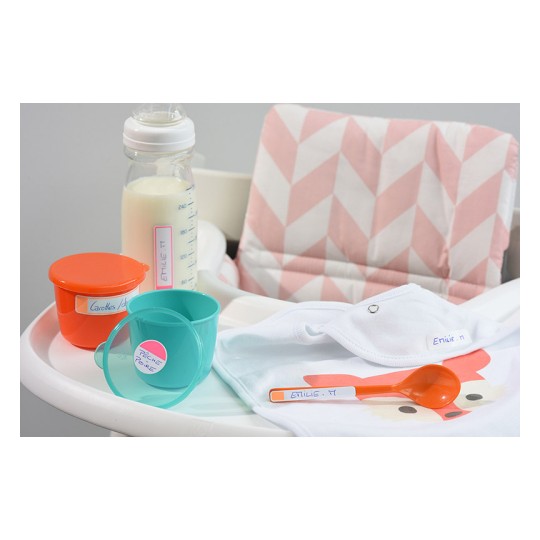 La imagen muestra un asiento para bebés con platos, un biberón de leche, un babero y una cuchara. Todo está etiquetado con el nombre 'Etilie'. El área de fondo tiene un diseño en tonos suaves.