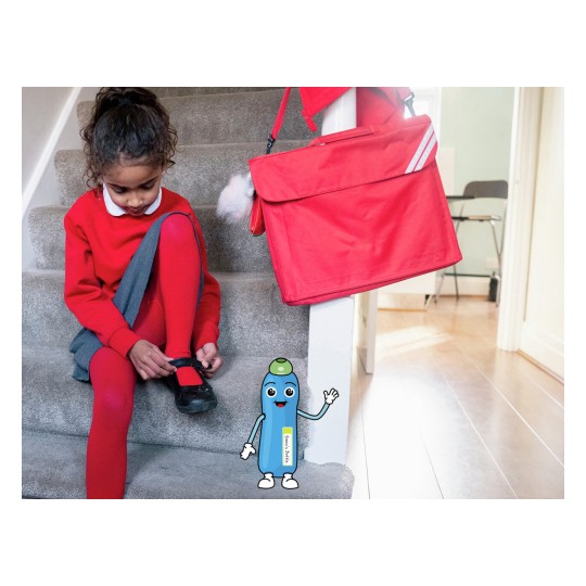 Una niña en escaleras con vestimenta roja, abrochándose un zapato. Tiene una mochila roja al lado. Hay un personaje animado al pie de la escalera.