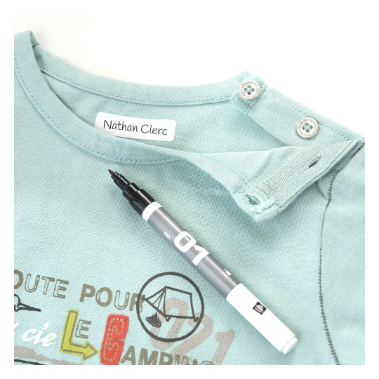 La imagen muestra una camiseta de color verde claro con el nombre 'Nathan Clerc' en la etiqueta. Junto a la camiseta hay un marcador negro.