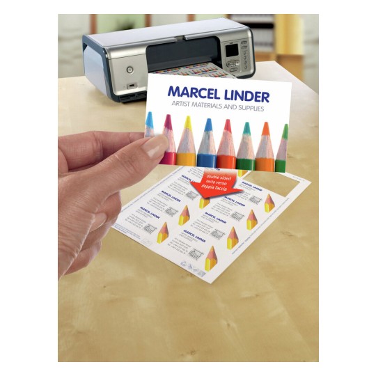 En la imagen se muestra una impresora, una persona sosteniendo una tarjeta que dice 'MARCEL LINDER ARTIST MATERIALS AND SUPPLIES', y una hoja impresa con varios diseños relacionados con materiales de arte.
