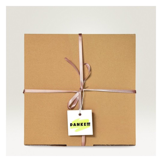 Una caja de regalo marrón con un lazo rosa y una etiqueta que dice 'DANKE!!!'.