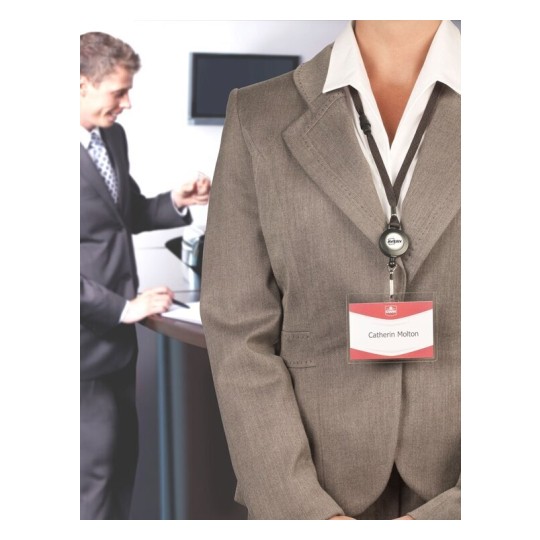 Una persona vestida con un traje formal y un gafete de identificación. En el fondo, otra persona está de pie, interactuando con una computadora. La identificación tiene el nombre 'Catherin Molton'.