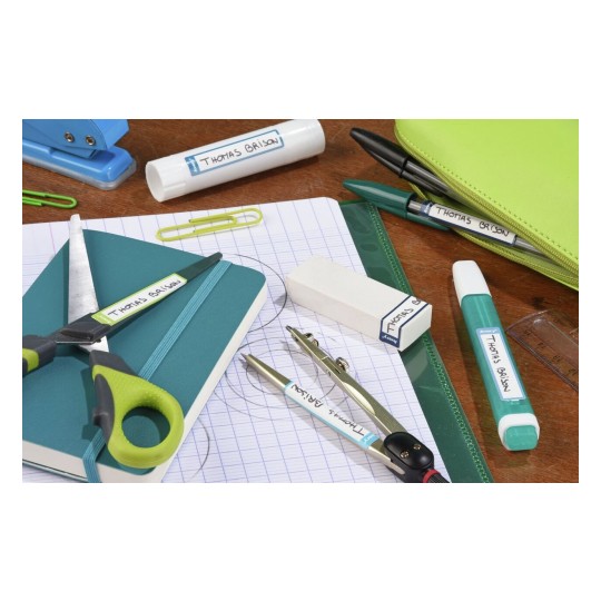 Una imagen que muestra varios útiles escolares desordenados sobre una mesa, incluyendo tijeras, una libreta, un lápiz, pegamento, un borrador, un compás y un bolígrafo en un estuche verde.