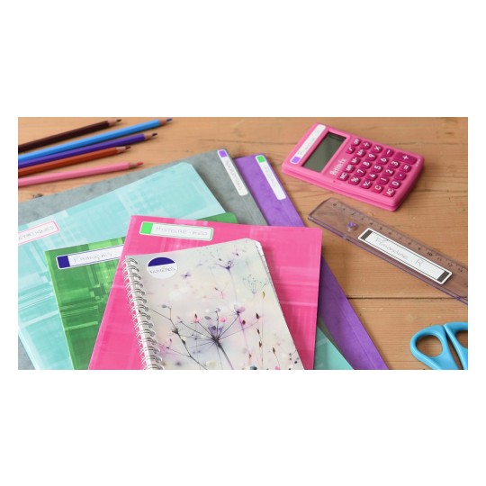 La imagen muestra varios cuadernos, una calculadora rosa, una regla, tijeras y lápices de colores sobre una mesa de madera.