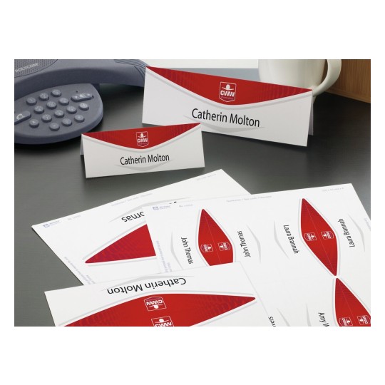 La imagen muestra tarjetas de presentación con nombres en una mesa, junto a un teléfono y una taza. Las tarjetas tienen un diseño rojo y blanco.