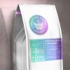 Paquete blanco de café con etiqueta informativa en tonos verdes y morados.
