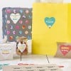 Varios regalos de cumpleaños envueltos y etiquetados con pegatinas de corazón sobre una mesa blanca