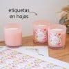 Tres velas rosa claro, dos con etiquetas florales cuadradas, sobre madera con hoja de etiquetas cuadradas personalizadas.