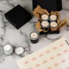 Envases de crema dispuestos sobre una mesa, decorados con etiquetas de acabado perlado