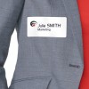 La imagen muestra una etiqueta de identificación con el nombre 'Julia SMITH' y el texto 'Marketing', colocada sobre una chaqueta gris con una parte roja visible detrás.