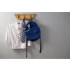 En la imagen se ve una camisa blanca, una corbata amarilla y azul, y una mochila azul, colgados en un perchero de madera.