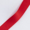 La imagen muestra una cinta roja de textura suave y brillante, dispuesta en una curva sobre un fondo claro. Este tipo de cinta se utiliza comúnmente en manualidades, regalos y decoraciones, agregando un toque elegante a cualquier proyecto.