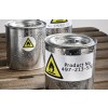 La imagen muestra latas de metal brillantes con etiquetas de advertencia que indican peligro de inflamabilidad. Las latas están mojadas y se encuentran sobre una superficie de madera.