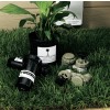 La imagen muestra una planta en una maceta, herramientas de jardinería y accesorios de riego sobre un césped verde.
