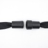 La imagen muestra dos extremos de un cordón negro con punteras de plástico negro, uno de los cuales está unido al cordón y el otro está separado, mostrando la estructura del dispositivo utilizado para evitar que se deshilache.
