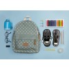 La imagen muestra una mochila con puntos, anteojos, un sacapuntas azul, lápices de colores, una cinta adhesiva, y un zapato con un personaje animado al lado.