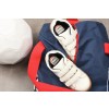 En la imagen se pueden ver un balón de fútbol, un par de zapatillas deportivas blancas y una bolsa de deporte azul con rojo. Las zapatillas tienen etiquetas visibles con el nombre 'Gabriel' y 'Judo'.