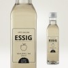 Una botella de vinagre de manzana. Etiqueta indica '100 % Äpfel | BIO', volumen de 250 ml, marca 'Junge Küche'.